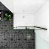 A top-down view of a shower enclosure with black framing and a glass door, set against dark tiled flooring and white tiled walls. Produktbild-Vorschau