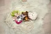 Several plush toys are arranged on a fluffy white rug, with a strand of yarn forming a heart shape in the foreground. Produktbild-Vorschau