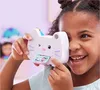 A young girl is holding a toy camera shaped like a cat and looking through the viewfinder. Produktbild-Vorschau