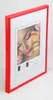 A red picture frame with a picture of a woman's face and macarons inside. Produktbild-Vorschau