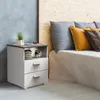 A bedside table with drawers next to a bed with pillows. Voir les images du produit