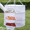 A person's hand is shown reaching into a three-tiered hanging drying rack filled with dried food items. Anteprima dell’immagine prodotto