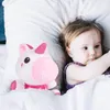 A baby lying in bed with a plush unicorn toy. Anteprima dell’immagine prodotto