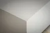 A close-up view of a corner where two walls meet, with a hint of a textured surface on the right. Produktbild-Vorschau
