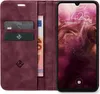 A burgundy flip case wallet for a smartphone is shown open, displaying cards and a banknote, with the smartphone screen illuminated. Produktbild-Vorschau