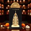 A perfume bottle shaped like a building, displayed with decorative elements like oranges and cinnamon sticks. Voir les images du produit