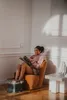 A woman is sitting in an armchair with her feet in a foot bath, reading a magazine. Náhľad obrázku produktu