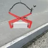 A red stone clamp is lifting a white concrete block over a paved surface. Podgląd zdjęcia produktu