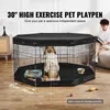 A dog is inside a black hexagonal pet playpen with a black cover. A person is sitting on a couch in the background. Produktbild-Vorschau
