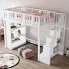 A white loft bed with a desk and shelves underneath, set up in a room with a rug and ottoman. Produktbild-Vorschau