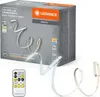The image shows the packaging of an LED strip light product, with the product itself partially uncoiled and displayed in front of the box. A remote control is also shown. Anteprima dell’immagine prodotto