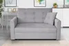 A gray sofa is shown in a well-lit room with a desk and pictures in the background. Náhľad obrázku produktu