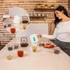A person pouring water from an electric kettle into a glass. Produktbild-Vorschau