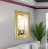 A gold-framed mirror hangs on a light gray wall above a white sofa, with a green plant in the foreground. Produktbild-Vorschau