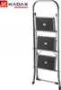 A folded steel step stool with three anti-slip steps, shown against a white background. The brand logo 'KADAX WORKSHOP' is visible in the top left corner. Podgląd zdjęcia produktu