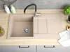 A beige granite kitchen sink with a black faucet, a draining board, and a sink basin. There are also some pears and an avocado on the counter. Produktbild-Vorschau