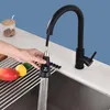 A hand is shown using a black kitchen faucet with a digital display, with fruit on a drying rack in the foreground. Produktbild-Vorschau