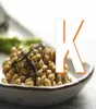 A close-up of a bowl of natto (fermented soybeans) with some seaweed on top, with a large white letter 'K' overlaid on the right side of the image. Voir les images du produit