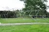 A metal frame for a greenhouse or tunnel is set up on a grassy lawn with a stone path in the foreground. Náhled obrázku produktu
