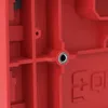 A close-up view of a red plastic tool box with a metal insert in a circular hole. Produktbild-Vorschau