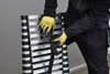 A person wearing yellow gloves is shown adjusting a strap on a folded aluminum ladder. Náhľad obrázku produktu