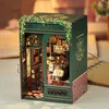 A miniature model of a bookstore with an open door, displaying shelves filled with books, furniture, and decorative items. Produktbild-Vorschau
