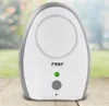 A reer baby monitor is placed on a wooden surface with a blurred outdoor background. Produktbild-Vorschau