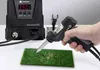 A hand holding a desoldering gun over a circuit board, with a digital desoldering station in the background. Produktbild-Vorschau