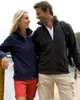 A couple standing on a wooden dock by a body of water, looking at each other and smiling. Produktbild-Vorschau