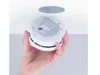 A hand is holding a smoke detector near a ceiling mount. Produktbild-Vorschau