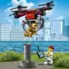 A LEGO City police drone is shown in mid-air, carrying a golden cat. A LEGO minifigure is operating the drone with a remote control. Produktbild-Vorschau