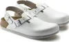 A pair of white Birkenstock Tokio clogs with a strap and buckle closure, shown from a slightly elevated side angle against a white background. Produktbild-Vorschau