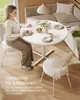 A woman is sitting at a round dining table set for four people in a modern dining room. Produktbild-Vorschau