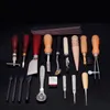 A collection of leatherworking tools laid out on a black surface. Voir les images du produit