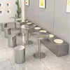 A cafe or restaurant seating area with small round tables and stools, and a long bench with cushions. Produktbild-Vorschau