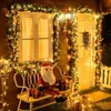 A festive Christmas decoration scene with a Santa Claus figure on a bench, surrounded by lights and garlands. Produktbild-Vorschau