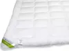 A close-up, angled view of a white quilted comforter or duvet, with a green and white tag attached to the corner. Podgląd zdjęcia produktu