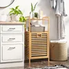 A bathroom scene with a laundry basket, drawers, and a plant. Podgląd zdjęcia produktu