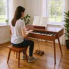A woman plays a digital piano in a well-lit room with large windows. Produktbild-Vorschau