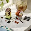 Two LEGO BrickHeadz figures, Aragorn and Arwen, are displayed on a white surface next to scattered LEGO bricks and a small toy sword. Produktbild-Vorschau