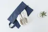 A pair of white sneakers is placed inside a blue denim organizer bag, which is laid open on a white surface. A small potted succulent plant is visible to the right. Anteprima dell’immagine prodotto
