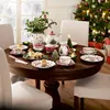 A Christmas-themed table setting with a tea set, cupcakes, and a Christmas tree in the background. Produktbild-Vorschau