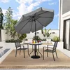 An outdoor patio scene with a table and chairs set under a large umbrella. Produktbild-Vorschau