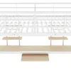 A close-up, straight-on view of the lower section of a white metal bunk bed frame, showing the slatted mattress support and two small wooden shelves attached to the frame, with a larger wooden shelf below. Produktbild-Vorschau
