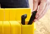 A hand is placing a black accessory into a yellow tool. Náhľad obrázku produktu