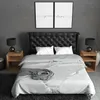 A modern bedroom with a tufted headboard, bedside tables, lamps, and framed artwork. Produktbild-Vorschau