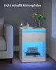 A modern white nightstand with blue LED lighting is placed next to a white sofa in a dimly lit room. Produktbild-Vorschau