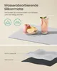 A top-down view of a light gray silicone mat with a glass of pink drink and sliced apples on it, along with a layered diagram of the mat's materials. Produktbild-Vorschau