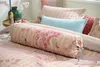 A close-up view of a bed with several pillows and bedding, featuring a floral pattern. Produktbild-Vorschau