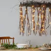 A table setting with a decorative branch and LED lights hanging above, with greenery and tableware. Podgląd zdjęcia produktu